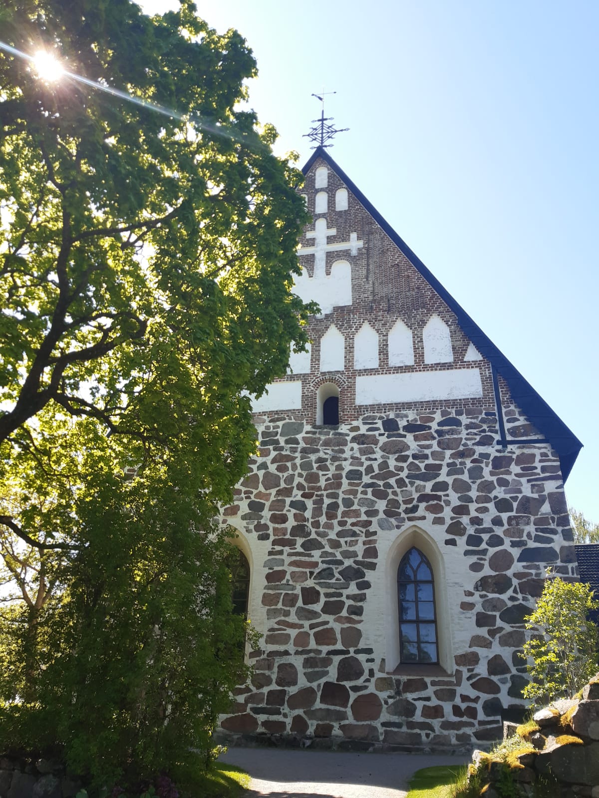 Hollolan kirkko auringonpaisteessa ja puut vihertää