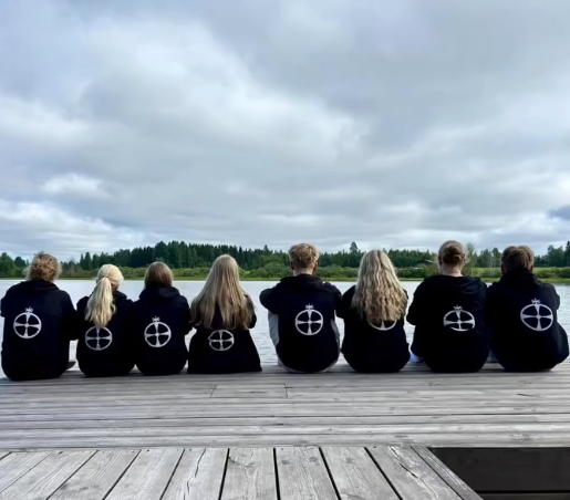 isoset istuvat laiturilla isos-hupparit päällä. Huppareissa on Hollolan seurakunnan vihkiristi selässä.